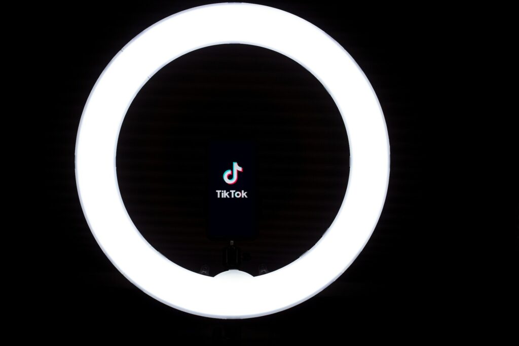 TikTok’s musical note logo and brand name are centered inside a ring light.