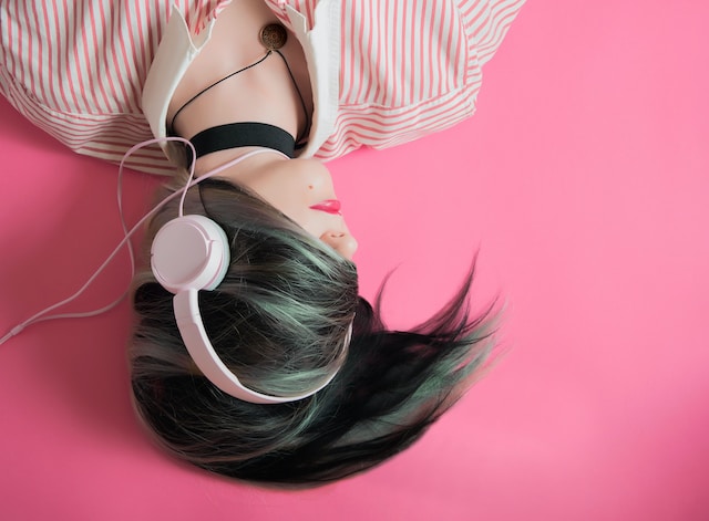 A woman listening to music with white headphones.