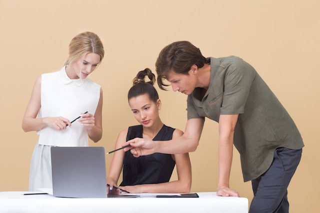 Three young professionals looking at a laptop screen.