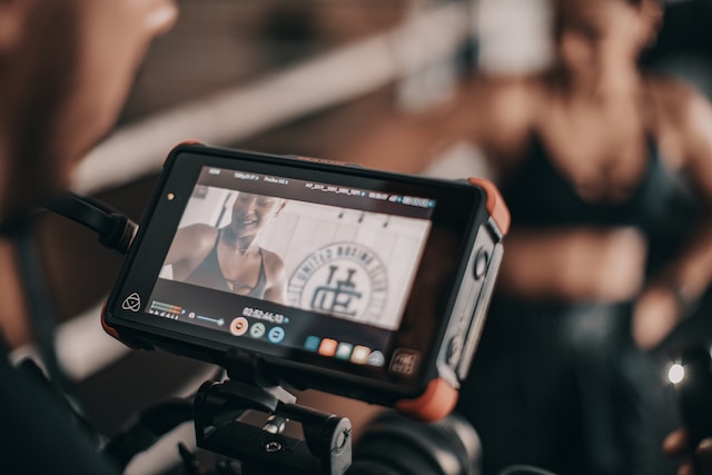A professional camera capturing a live workout video.