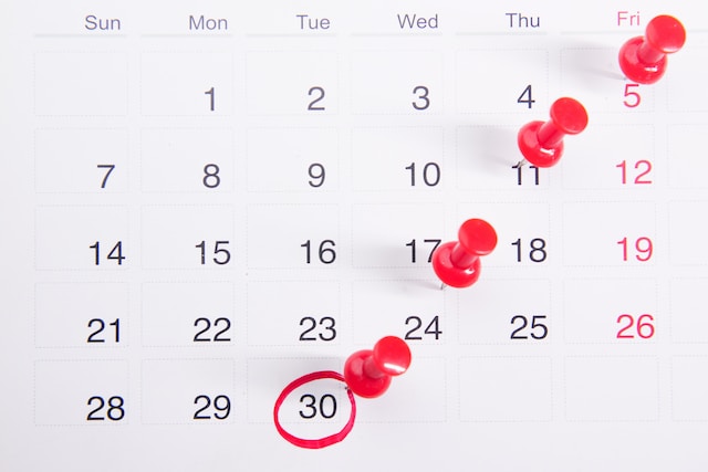 A calendar with red push pins.