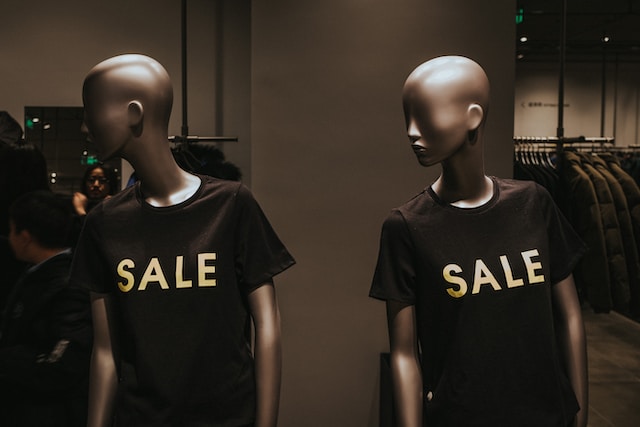 Two mannequins wearing black shirts with the word “Sale” printed on them.