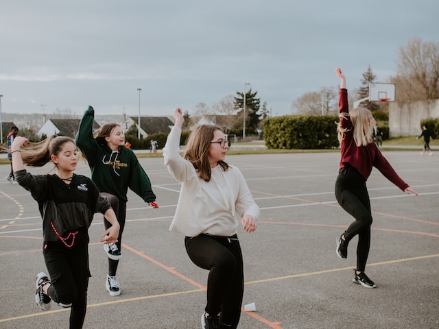 A group of girls practicing a dance in a parking lot.