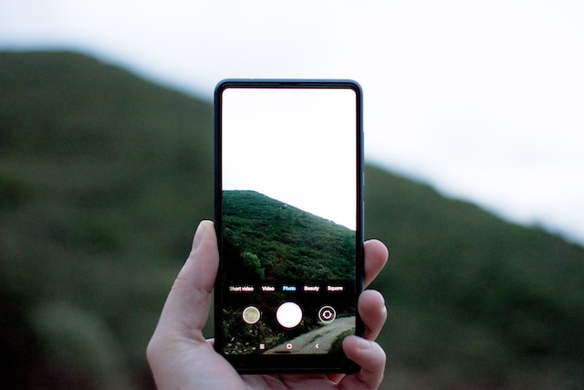 A person taking a photo with their phone in portrait mode.