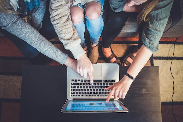 A group of women reading online comments on a laptop.