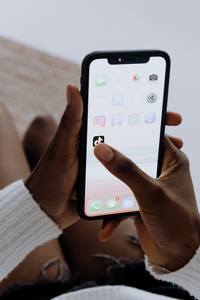 A person clicking on the Tik Tok application on a smartphone.
