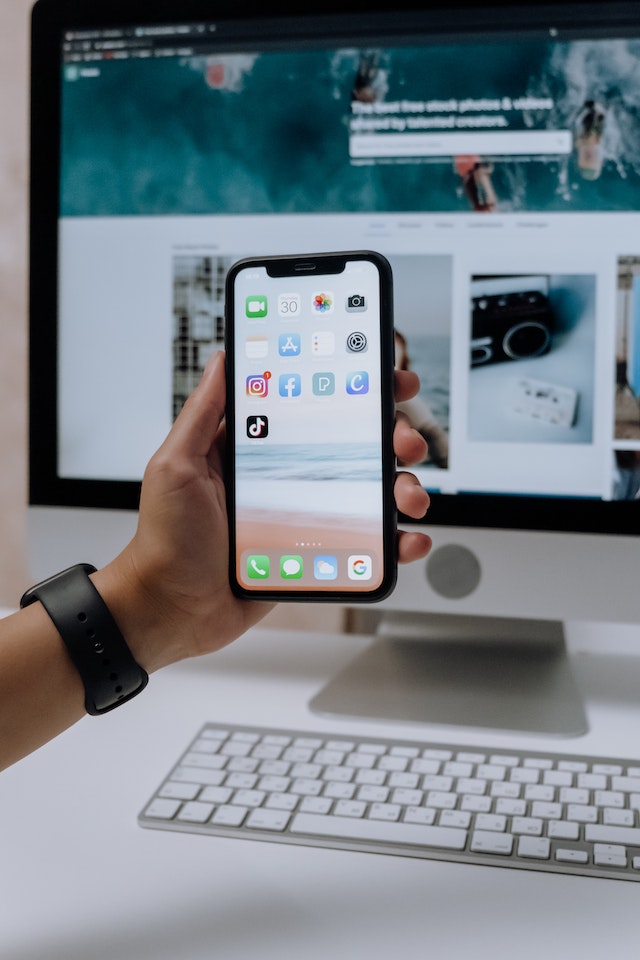 Someone holding a phone while with the TikTok app and other apps on the screen.