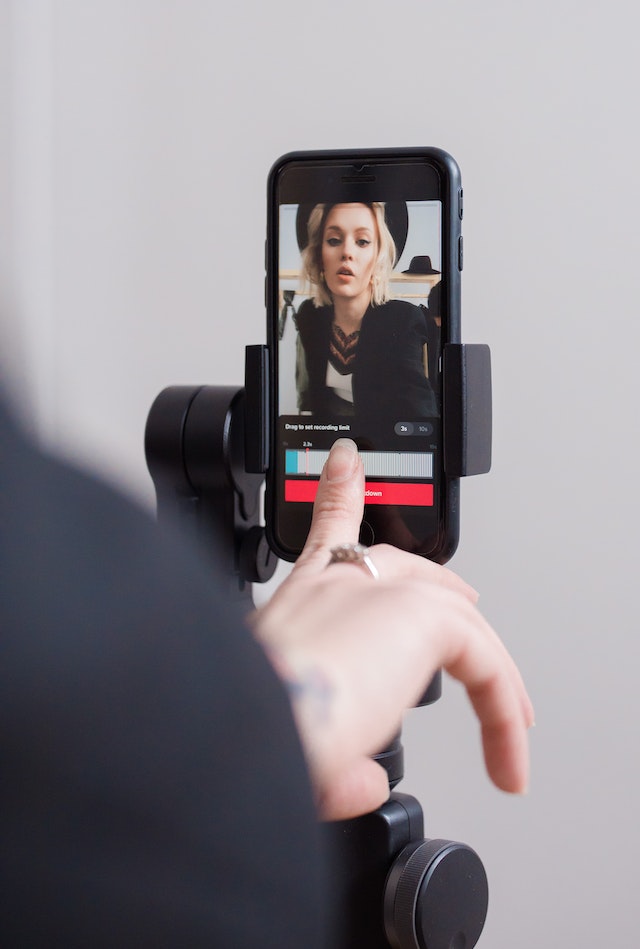 A girl using a black smartphone to record a TikTok Video.