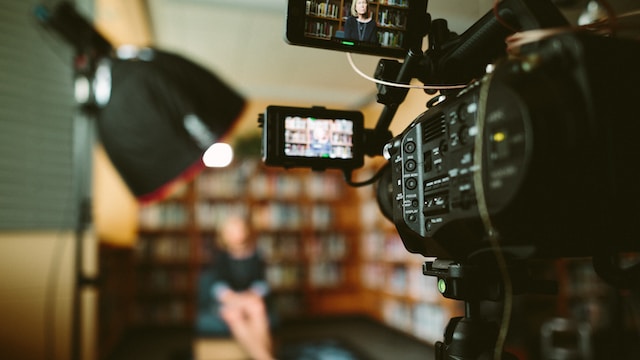 A person sitting in a library in front of a camera for a live stream.