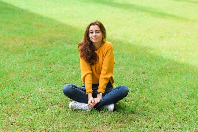 A girl sitting on the grass posing for a picture.