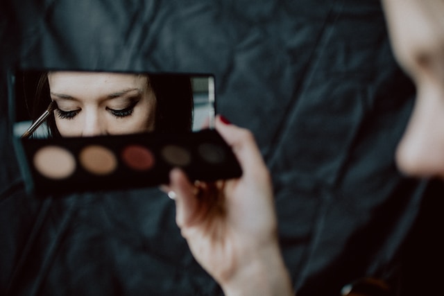 A woman putting on eye makeup for a tutorial video.