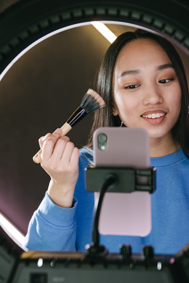 A girl recording herself doing makeup for a TikTok video.