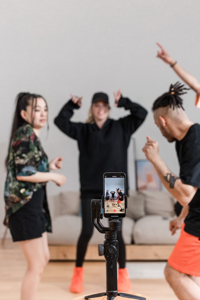 A group of people dancing for a TikTok video and recording themselves.
