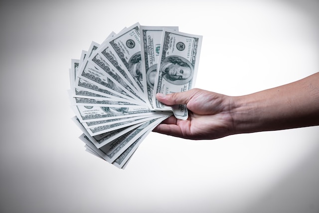 A person holding 100-dollar bills.