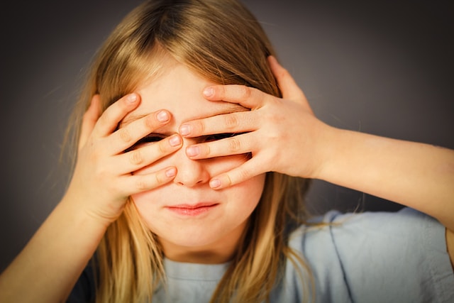 A young girl covering her eyes.