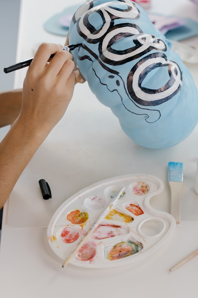 A person decorating a blue pumpkin for Halloween.