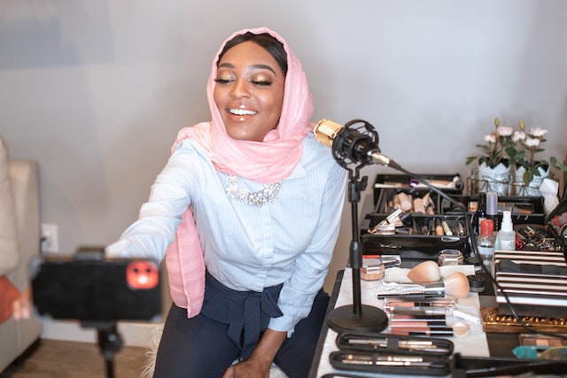A girl wearing a scarf and recording a video for TikTok.