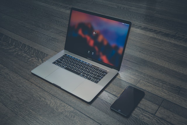 A laptop and an iPhone on a flat surface.