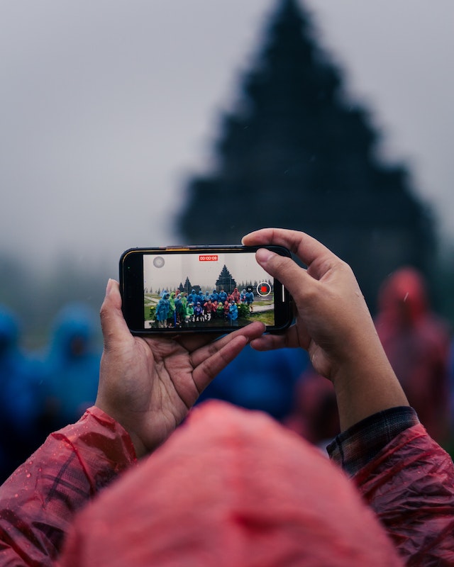 A person recording a video of a group of people for TikTok.