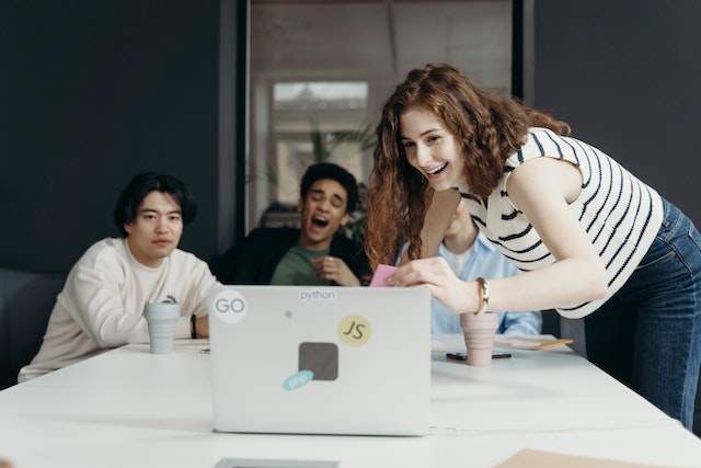 A group of friends laugh at a video they’re watching on a laptop.