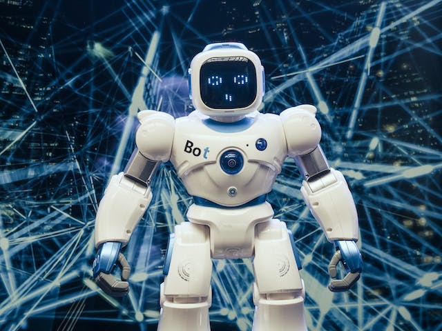 A photo of a small, white robot in front of intersecting blue lines.