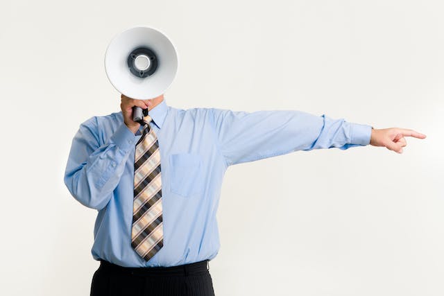 A person holds a megaphone in front of his face.