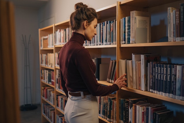 A girl searching for her next story from the bookshelf.