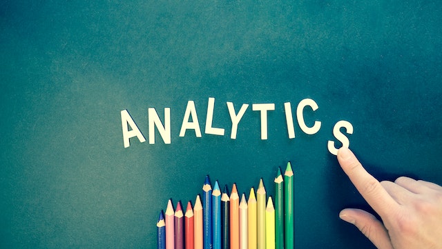 A person arranges letter tiles that spell “ANALYTICS.”