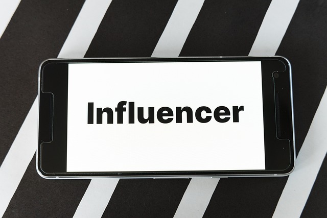 Image of an Android phone on a black and white stripe background with the word influencer on its screen.