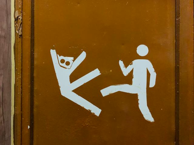 A door features a drawing of a human figure kicking another.