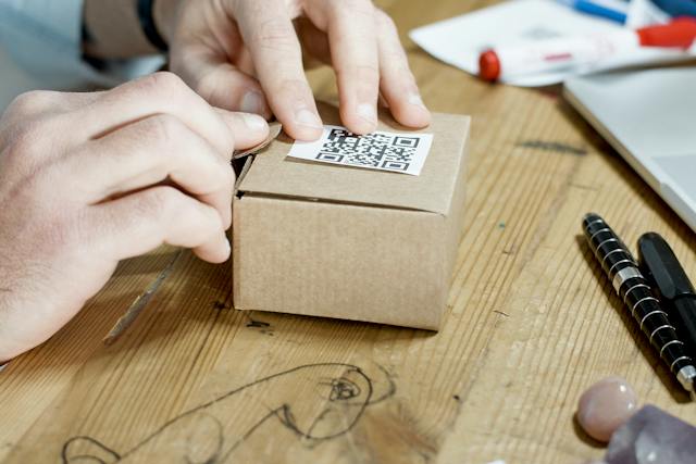 A person puts a sticker with a QR code on a product packaging.