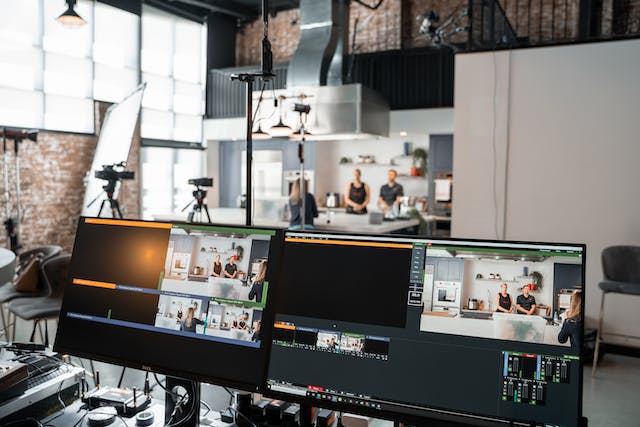 A photo of a LIVE stream set up with computer monitors, video cameras, and lights.