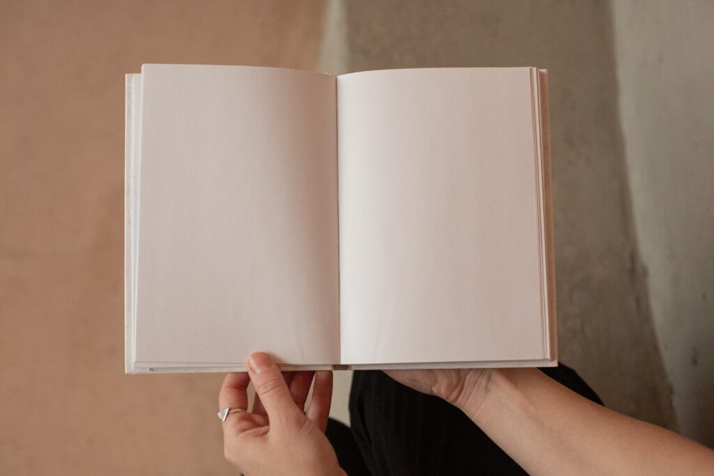 A person holds a notebook with blank pages.