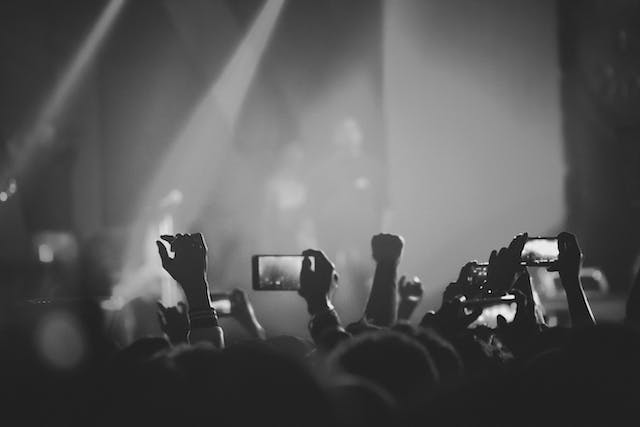 Audiences taking photos and videos at a live event.