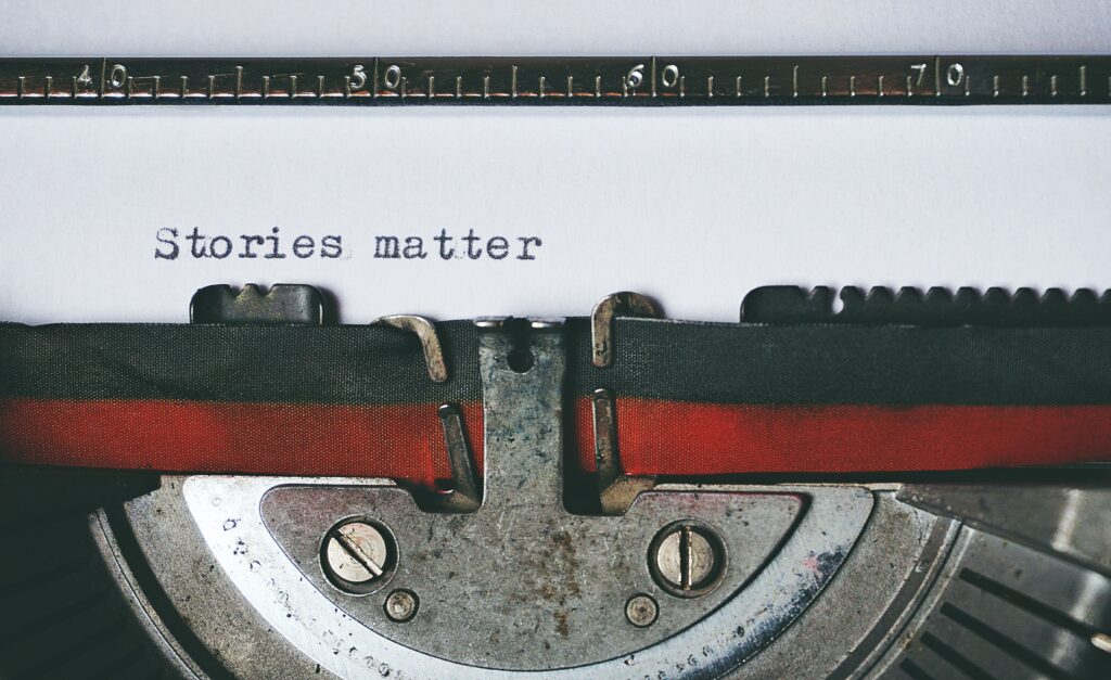 A photo of a piece of paper in a typewriter with the words “Stories matter” printed.