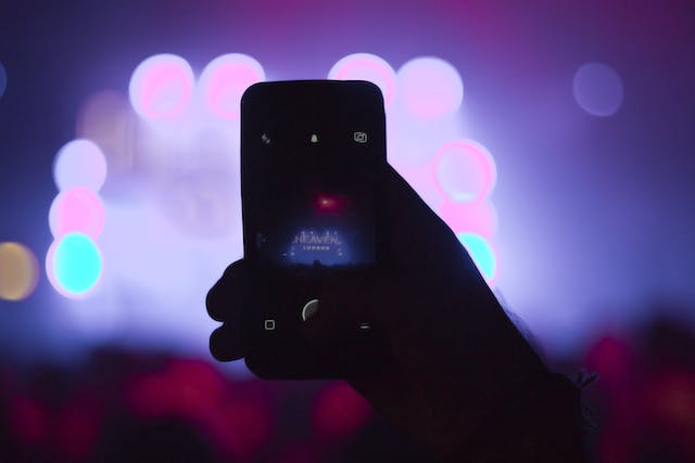 A person broadcasts a concert LIVE using their phone.