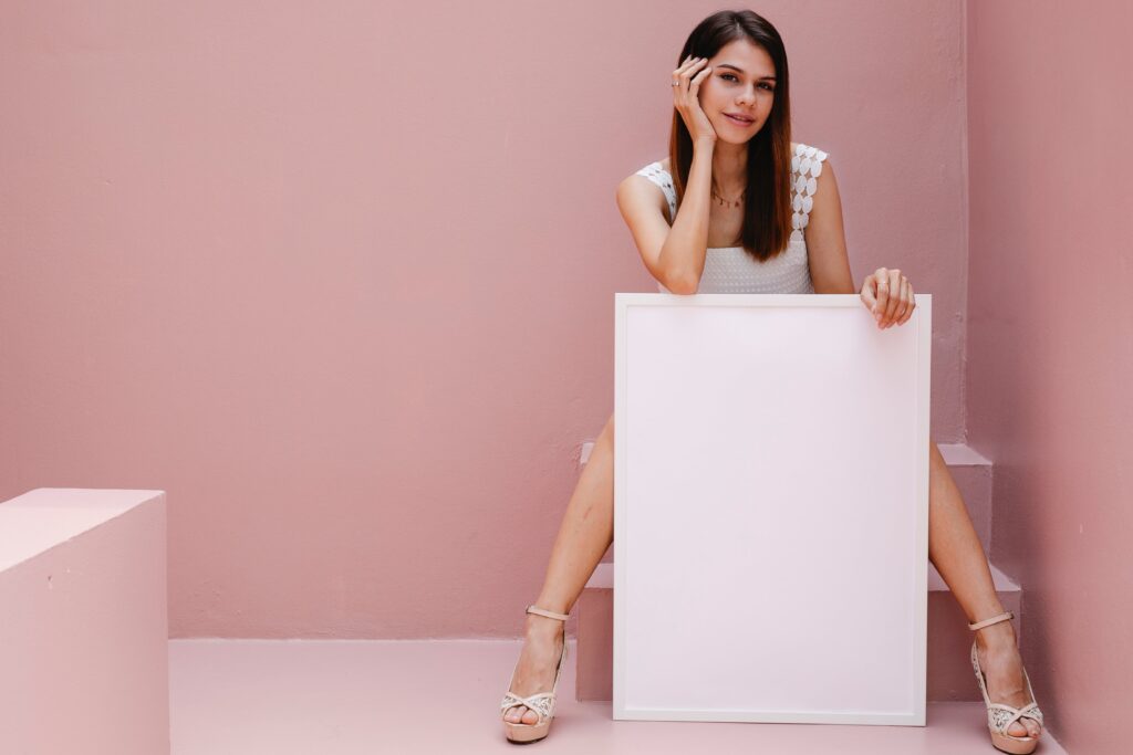 A woman sits on a set of stairs while holding a blank canvas for an ad.