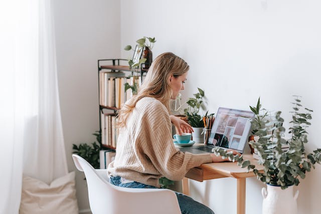 A woman browses through photos on her laptop to create a TikTok slideshow.