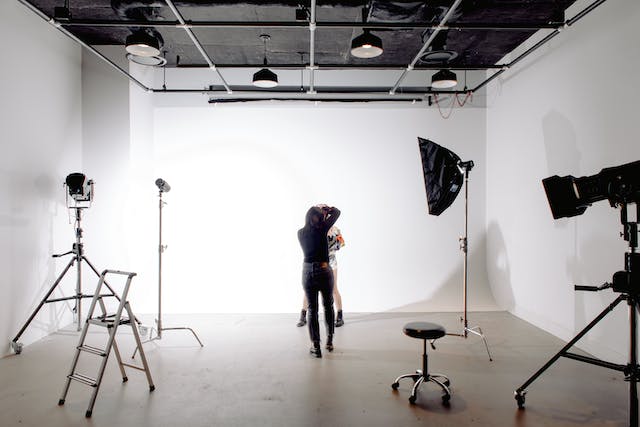 A professional photographer takes photos of a model in a studio.