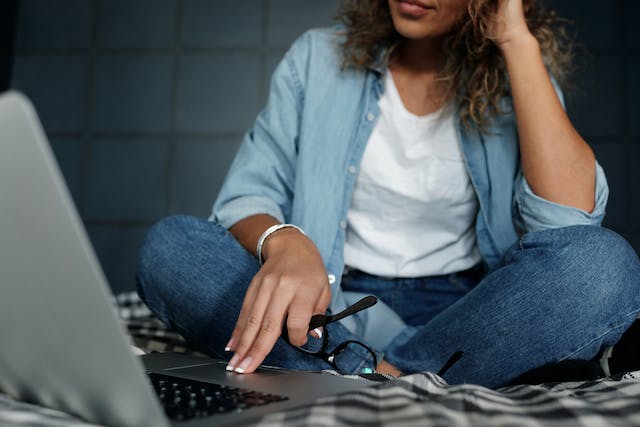 A woman sits in front of her laptop.