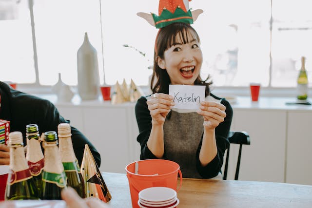 A woman happily holds up a piece of paper with a name on it.