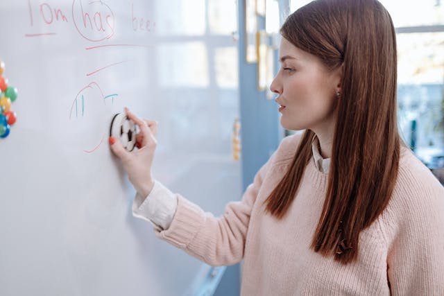 A woman erases a whiteboard.