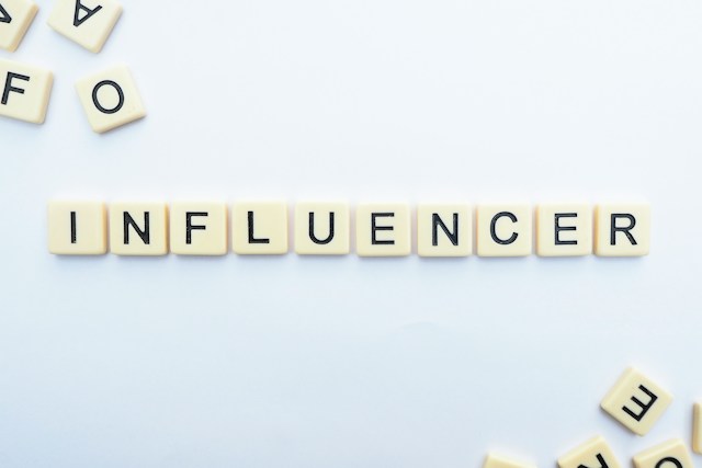 Scrabble tiles on a white surface spelling out the word “INFLUENCER.”
