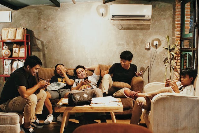 Friends lounge on couches while they use their mobile phones.