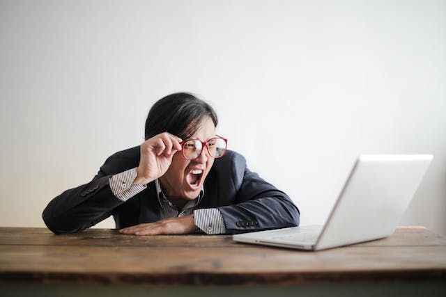 A person looks surprised while watching videos on their laptop.