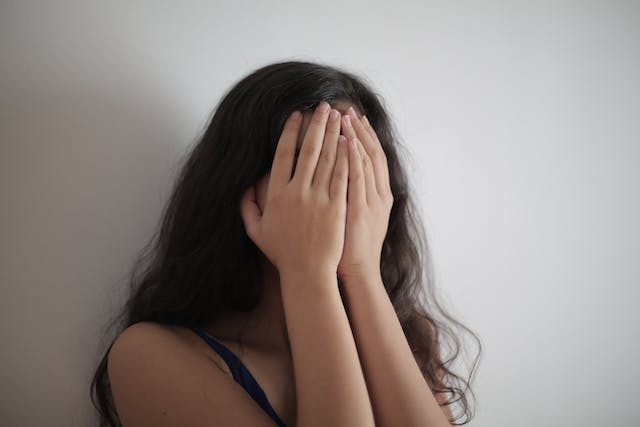 A woman covers her face with her hands.