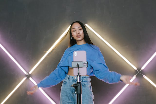 A young woman performs in front of her phone for her TikTok followers.