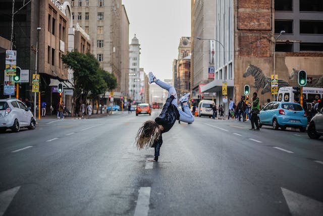A photo of a woman breakdancing in the middle of a street.