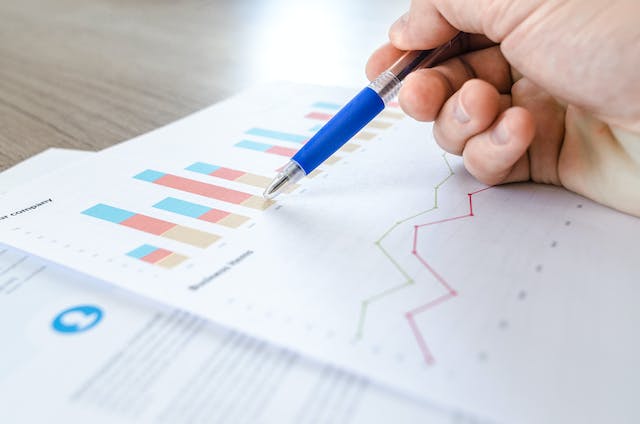 A person studies bar and line graphs printed on paper.