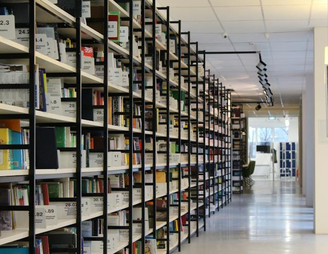 A long library aisle full of shelves stacked with books.